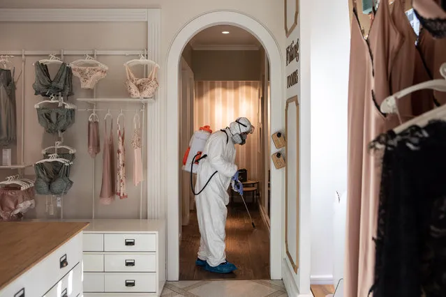 A utility service worker, wearing a protective suit, sprays sodium hypochlorite to disinfect the fitting rooms of a women underwear store on April 29, 2020 in Milan, Italy. Italy will remain on lockdown to stem the transmission of the Coronavirus (Covid-19), slowly easing restrictions. (Photo by Emanuele Cremaschi/Getty Images)
