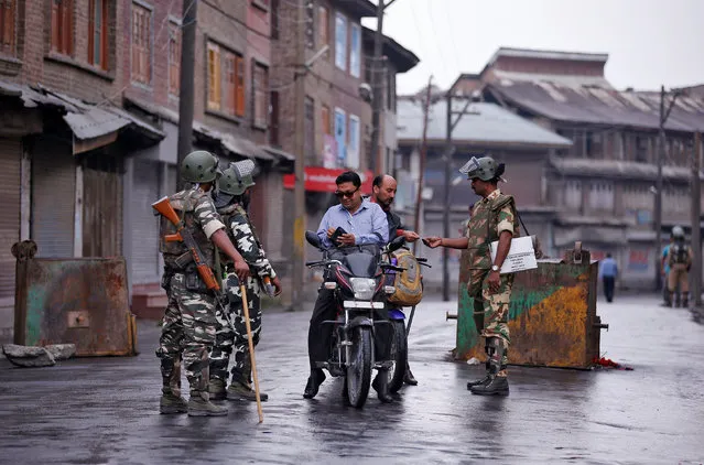 Indian policemen check identity papers of Kashmiri men on their motorcycles during a curfew in Batamaloo area of Srinagar August 2, 2016. (Photo by Danish Ismail/Reuters)