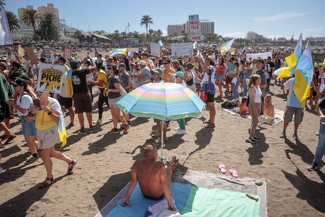 Protesters march on Las Americas beach during a demonstration to protest against mass tourism, in Arona on the Spanish Canary island of Tenerife, on October 20, 2024. Thousands of flag-waving demonstrators hit the streets across Spain's Canary Islands today to demand changes to the model of mass tourism they say is overwhelming the Atlantic archipelago. 
Rallying under the slogan “The Canary Islands have a limit”, demonstrators waving white, blue and yellow flags of the Canary Islands, marched by tourists sitting in outdoor terraces in Playa de las America before they rallied on the beach chanting “This beach is ours” as tourists sitting on sunbeds under parasol shades looked on. (Photo by Desiree Martin/AFP Photo)