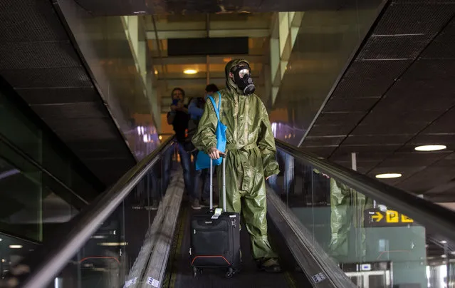A passenger wearing a full protective suit arrives from London at the Barcelona airport, Spain, on Friday, May 15, 2020. Travellers arriving in Spain from overseas start from Friday going into a 14-day confinement as the country takes timid steps toward re-opening borders with eyes set on reactivating the crucial tourism industry. (Photo by Emilio Morenatti/AP Photo)