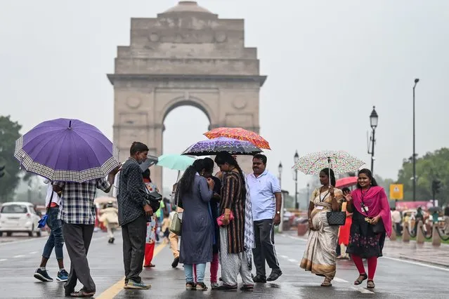 People use umbrellas as they visit they newly inaugurated central vista project near India Gate during a rainfall in New Delhi in September 23, 2022. (Photo by Money Sharma/AFP Photo)
