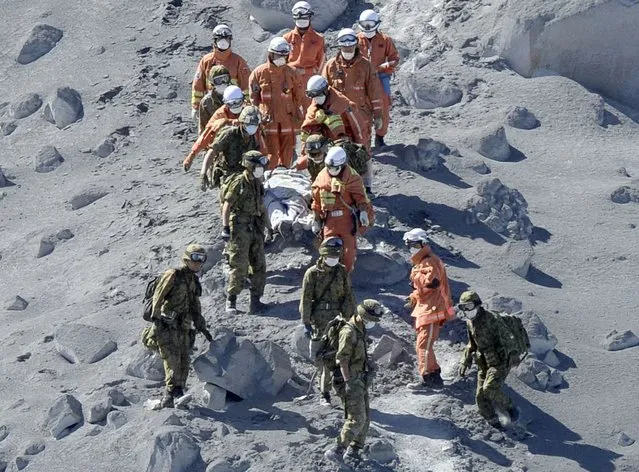 Japan Self-Defense Force (JSDF) soldiers and firefighters carry an injured person near a crater of Mt. Ontake, which straddles Nagano and Gifu prefectures in this September 28, 2014 photo taken and released by Kyodo. (Photo by Reuters/Kyodo News)