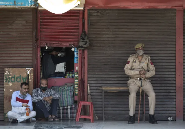 A policeman wearing a mask as a protection against the coronavirus keeps guard outside a half-closed shop in Srinagar, Indian controlled Kashmir, Tuesday, June 9, 2020. (Photo by Mukhtar Khan/AP Photo)