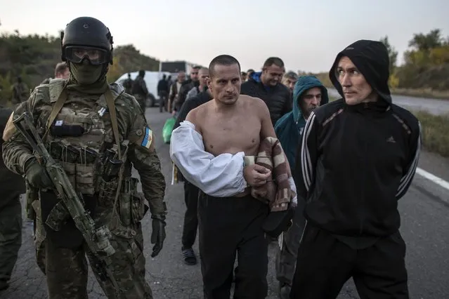 A Ukrainian soldier (L) stands guard as members of the pro-Russian rebels, who are prisoners-of-war (POWs), walk along a road as they wait to be exchanged, north of Donetsk, eastern Ukraine, September 28, 2014. (Photo by Marko Djurica/Reuters)