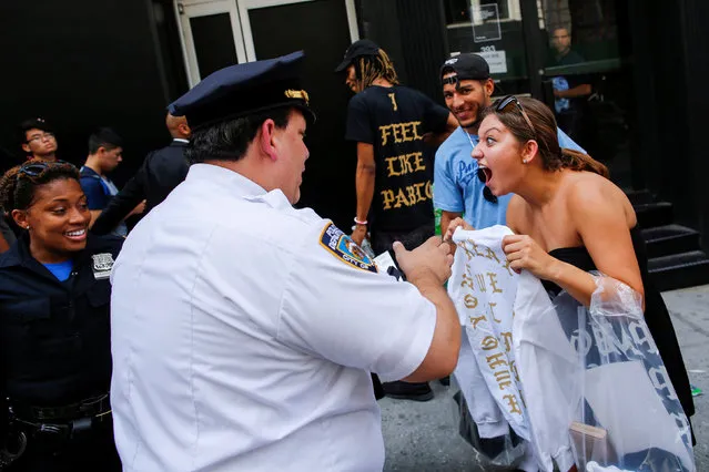 A shopper shows her “The Life of Pablo” merch to NYPD officers after visiting a pop up store featuring fashion by Kanye West in Manhattan, New York, U.S., August 19, 2016. (Photo by Eduardo Munoz/Reuters)