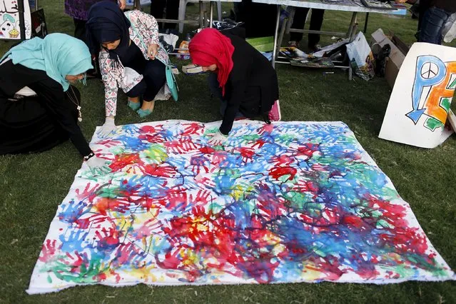 Women make handprint art during a festival commemorating the International Day of Peace in Baghdad, September 21, 2015. (Photo by Thaier al-Sudani/Reuters)