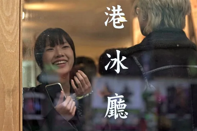 Customers wait near the words “Hong Kong Ice Cafe” at the HOKO Cafe, a pop-up cafe in the trendy London neighborhood of Shoreditch that's attracting Londoners and tourists as well as Hong Kong emigres on November 18, 2022. As tens of thousands leave Hong Kong for new lives abroad, many are craving a flavor from childhood that's become a symbol of the city's culture: the sweet, heavy tea with evaporated milk that's served both hot and cold at diner-like restaurants called cha chaan tengs. Workshops are popping up to teach professionals to brew tea like short-order cooks, and milk tea businesses are expanding beyond Chinatowns in Britain. (Photo by Kin Cheung/AP Photo)