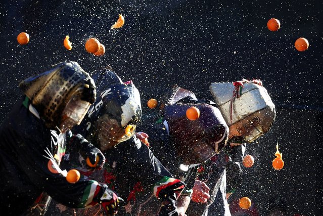 Revellers take part in a fight with oranges during an annual carnival battle in Ivrea, Italy, on February 11, 2024. (Photo by Guglielmo Mangiapane/Reuters)