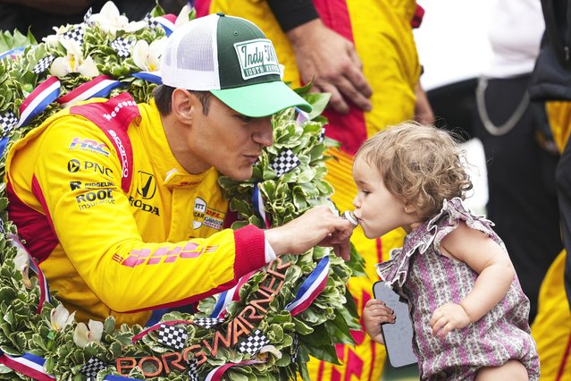 Alex Palou, left, of Spain, has his winner's ring kissed by his daughter Lucia on the Yard of Bricks on the start/finish line after winning the Indianapolis 500 auto race at Indianapolis Motor Speedway in Indianapolis, Sunday, May 25, 2025. (Photo by AJ Mast/AP Photo)