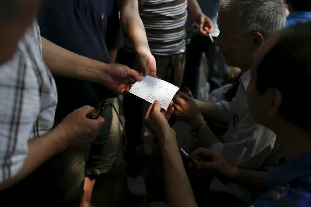 A piece of paper stock information written on it is shared by investors during a “street stock salon” in central Shanghai, China, June 20, 2015. (Photo by Aly Song/Reuters)