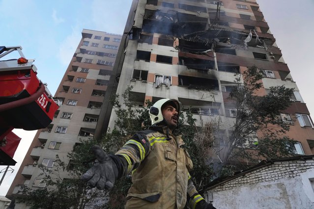 A firefighter calls out his colleagues at the scene of an explosion in a residence compound in northern Tehran, Iran, Friday, June 13, 2025. (Photo by Vahid Salemi/AP Photo)