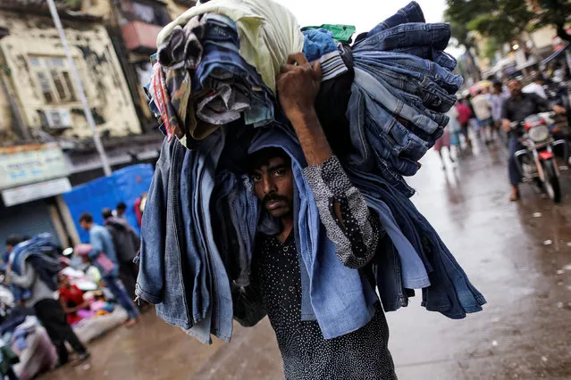 A man carries used clothes before they are sold at a second-hand clothing market in Mumbai, India, September 19, 2016. (Photo by Danish Siddiqui/Reuters)