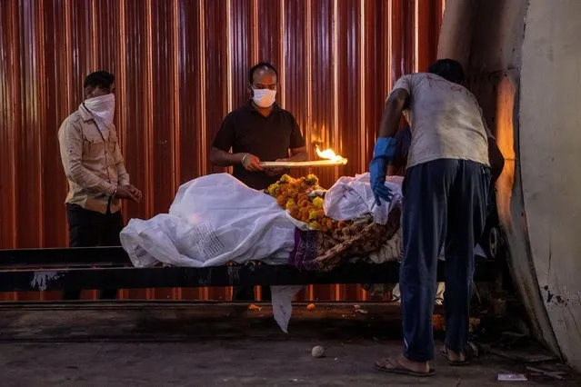 A relative performs the final rites of a woman, who died due to the coronavirus disease (COVID-19), at a crematorium in New Delhi, India, October 3, 2020. (Photo by Danish Siddiqui/Reuters)