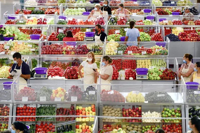 Fruit and vegetable vendors, wearing masks against the spread of the COVID-19 infections, wait for customers at a market in Bucharest, Romania, Tuesday, August 11, 2020. Romania is faced with an increasing number of COVID-19 infections and related deaths over the past weeks, the highest levels since the pandemic started in the country in February, blamed mostly on people not observing the prevention regulations, like correctly wearing a face mask. (Photo by Andreea Alexandru/AP Photo)