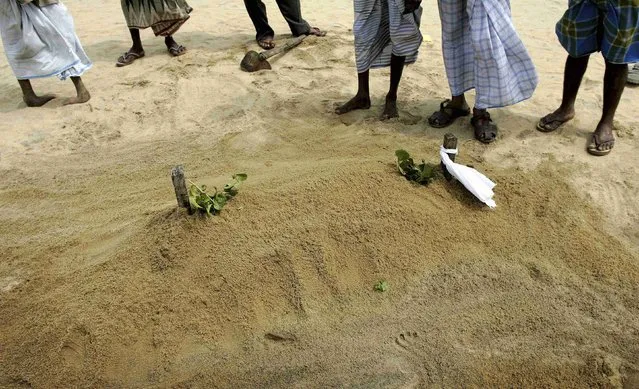 Muslims stand and pray at the grave of a young girl buried on Kalmunai beach following the December 26 tsunami on Sri Lanka's east coast in this January 7, 2005 file photo. (Photo by Kieran Doherty/Reuters)