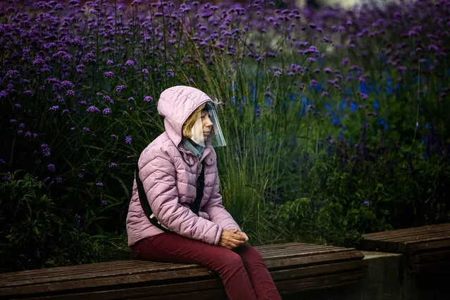 A woman wearing a face shield to protect against the coronavirus disease sits on a bench at an embankment of the Moskva river in Moscow on September 30, 2020. (Photo by Dimitar Dilkoff/AFP Photo)