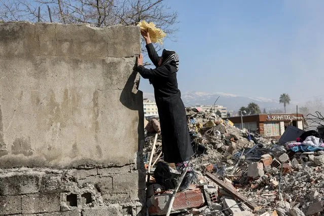 A woman takes bread out of the rubble of her house, in the aftermath of a deadly earthquake in Kahramanmaras, Turkey on February 14, 2023. (Photo by Nir Elias/Reuters)