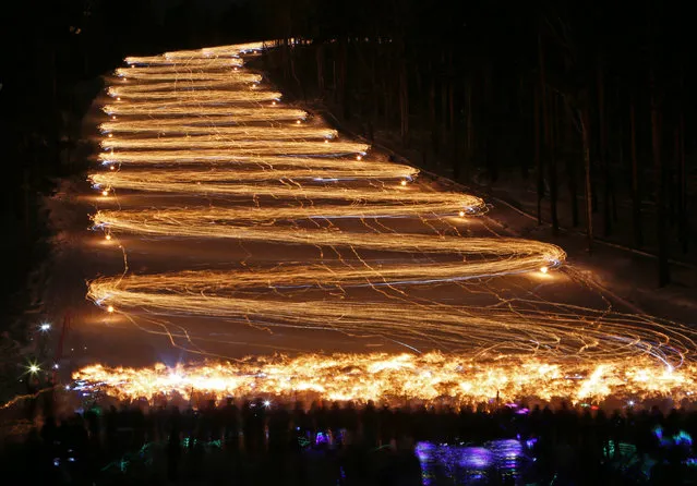Hundreds of skiers and snowboarders hold lit torches and flashlights while descending from a slope during an annual festival in the Siberian town of Zheleznogorsk near Krasnoyarsk, Russia March 3, 2018. Picture taken with long exposure on March 3, 2018. (Photo by Ilya Naymushin/Reuters)