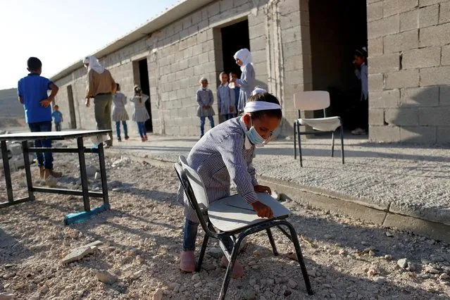 A Palestinian student wears a protective face mask as she moves a chair at Ras El-Teen School near Ramallah in the Israeli-occupied West Bank on October 11, 2020. (Photo by Mohamad Torokman/Reuters)