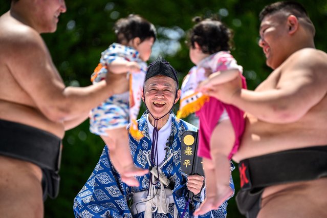 Sumo wrestlers hold children during their “crying baby sumo” match at Sensoji temple in Tokyo on April 28, 2024. (Photo by Philip Fong/AFP Photo)