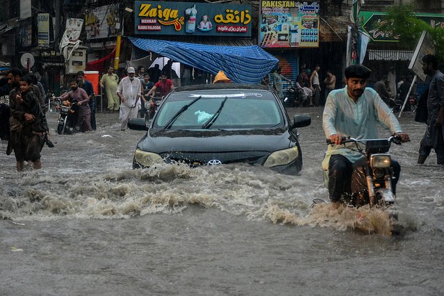 Commuters wade through a flooded street during heavy monsoon rains in Hyderabad, in Sindh province, on July 14, 2025. Monsoon rains in Pakistan have been linked to more than 110 deaths including dozens of children since they arrived in late June, according to government figures released on July 14. (Photo by Akram Shahid/AFP Photo)