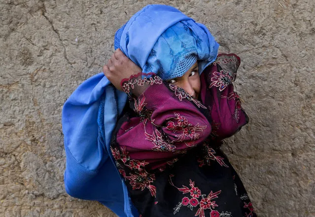 An Afghan girl adjusts her burqa as she plays with other children in the old town of Kabul, Afghanistan, Sunday, April 7, 2013. (Photo by Anja Niedringhaus/AP Photo)
