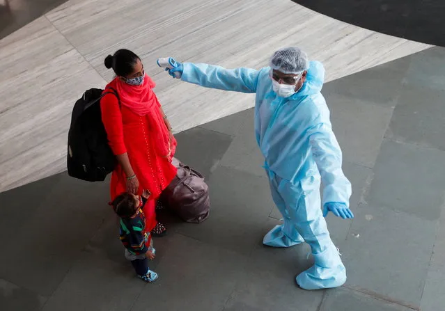 A health worker in personal protective equipment (PPE) checks the temperature of a passenger at a railway station, amid the spread of the coronavirus disease (COVID-19), in Mumbai, India on November 27, 2020. (Photo by Francis Mascarenhas/Reuters)