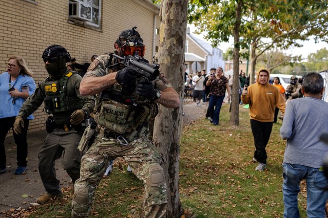 A federal agent points a "less lethal" munitions launcher at community members as they detain a man after clashes on Chicago’s South Side, on October 14, 2025. (Photo by Jim Vondruska/Reuters)