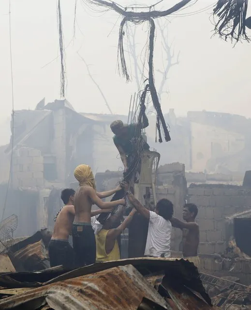 Residents recover copper from electric wires destroyed by a fire at a slum colony in Quezon city, Metro Manila January 1, 2015. (Photo by Erik De Castro/Reuters)