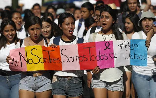 In this April 26, 2018 photo, students hold a sign that reads in Spanish “It's not three, it's all of us” during a protest against the murder of three film students who have become emblematic of Mexico's missing, in Guadalajara, Mexico. Prosecutors said the three were abducted by the Jalisco New Generation Cartel because they were filming a school project at a house used by the rival Nueva Plaza gang. The students were using the residence because it belonged to one of their aunts. (Photo by Eduardo Verdugo/AP Photo)