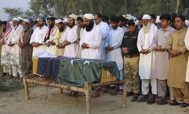 Local residents offer the funeral prayer of an intelligence officer in Charsadda, Pakistan, Monday, October 24, 2016. Police officer Khalid Khan says two gunmen on a motorcycle opened fire early on Monday, killing intelligence officer Akbar Ali in the Charsadda district of Khyber Pakhtunkhwa province. Khan says the attackers fled the scene. (Photo by Zia Muhammad/AP Photo)