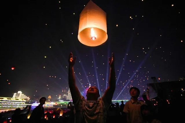 This photo taken on April 13, 2023 shows a man releasing a sky lantern to celebrate the New Year of the Dai ethnic minority in Xishuangbanna, in China's southwestern Yunnan province. (Photo by AFP Photo/China Stringer Network)