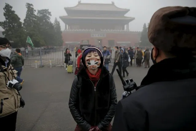 A girl wearing a protective mask talks to a policeman near the Forbidden City on an extremely polluted day as hazardous, choking smog continues to blanket Beijing, China December 1, 2015. (Photo by Damir Sagolj/Reuters)