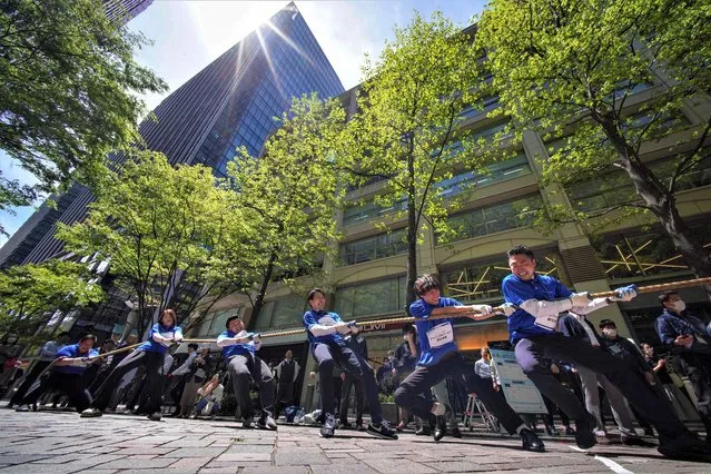 Office workers in Tokyo's Marunouchi business area compete in a tug-of-war match aimed at promoting health and interaction between companies and workers on April 17, 2023. (Photo by Kazuhiro Nogi/AFP Photo)