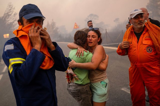 Women embrace after being rescued during a wildfire in Varnavas, north of Athens, on August 11, 2024. (Photo by Angelos Tzortzinis/AFP Photo)