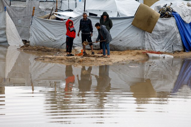 Displaced Palestinians stand near accumulated rainwater as they shelter in a tent camp on a rainy day in Nuseirat, central Gaza Strip, on December 12, 2025. (Photo by Mahmoud Issa/Reuters)
