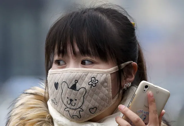 In this December 8, 2015 photo, a woman wears a mask to protect herself from pollutants on a heavily polluted day in Beijing. (Photo by Andy Wong/AP Photo)