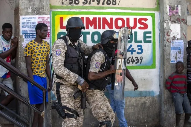 Police officers take cover behind a shield as they clash with demonstrators during a protest to demand the resignation of Haitian President Jovenel Moise in Port-au-Prince, Haiti, Sunday, February 7, 2021. (Photo by Dieu Nalio Chery/AP Photo)