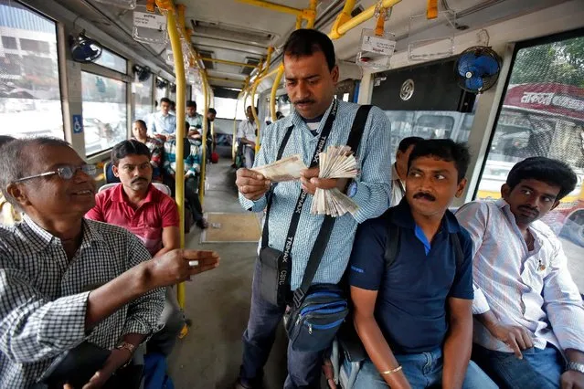 A government bus conductor checks a 500 Indian rupee banknote before issuing a ticket to a passenger in Kolkata, India, November 9, 2016. (Photo by Rupak De Chowdhuri/Reuters)
