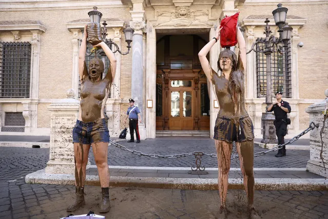 Climate activists of the “Last Generation” shower themselves with mud in front of the Senate building in Rome, Italy, Tuesday, May 23, 2023. (Photo by Cecilia Fabiano/LaPresse via AP Photo)