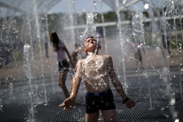 A boy plays with water fountains on a hot day in Volgograd, Russia, June 28, 2018. (Photo by Ueslei Marcelino/Reuters)