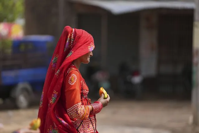 A nomadic woman walks eating a fruit on a hot summer afternoon in Lalitpur district in northern Uttar Pradesh state, India, Sunday, June 18, 2023. (Photo by Rajesh Kumar Singh/AP Photo)