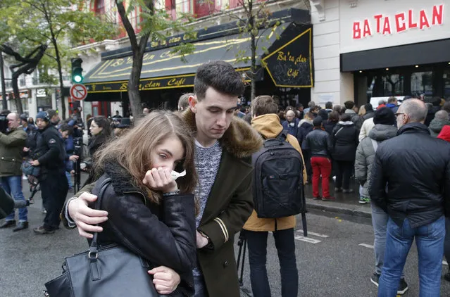 People console each at the Bataclan concert hall in Paris, Sunday, November 13, 2016. French President Francois Hollande has opened a national day of commemoration in France one year after the Paris attacks that killed 130. (Photo by Michel Euler/AP Photo)