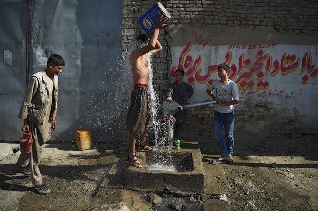 An Afghan youth cools off as he takes a shower next to a hand pump along the roadside in Kabul on June 13, 2018. (Photo by Wakil Kohsar/AFP Photo)