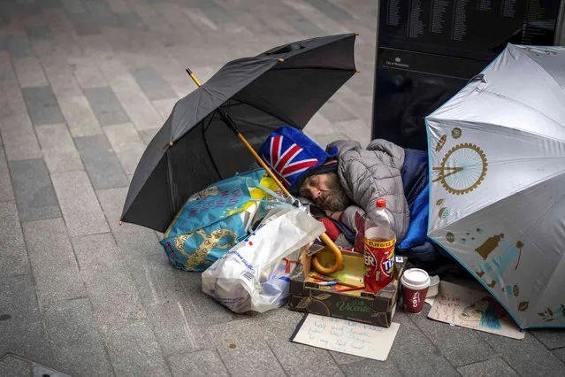 A man sleeps on the ground ahead of Britain's King Charles III coronation ceremony in London, Saturday, May 6, 2023. (Photo by Emilio Morenatti/AP Photo)