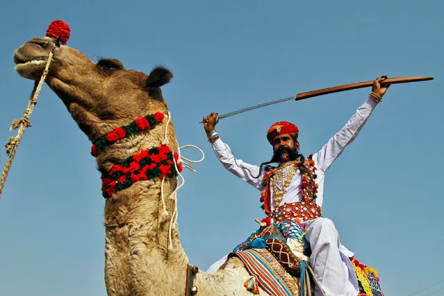 An artist displays a sword on the last day of Pushkar Fair, during which thousands of animals, mainly camels, are brought to the fair to be sold and traded, in the desert state of Rajasthan, India November 14, 2016. (Photo by Himanshu Sharma/Reuters)