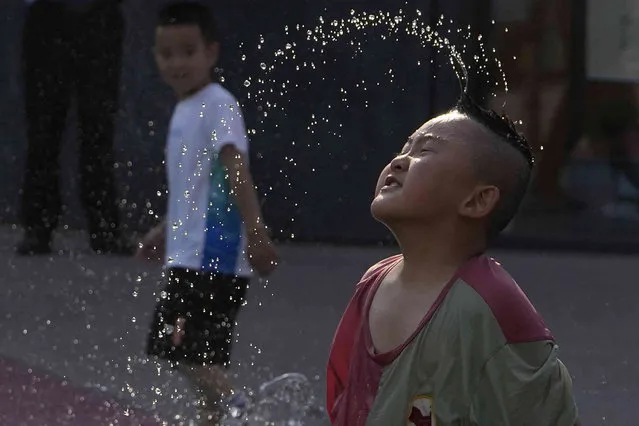 A child cools off playing at a fountain in Beijing, Friday, June 16, 2023. Local media reported that June temperatures in the Chinese capital broke its record with 39.4 celsius on Friday. (Photo by Ng Han Guan/AP Photo)
