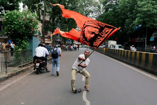 A man waves a flag as he blocks a road during a protest, organised by Maharashtra state's Maratha community, to press their demands for reserved quotas in government jobs and college places for students in Mumbai, India July 25, 2018. (Photo by Danish Siddiqui/Reuters)