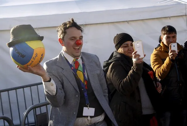 A member of Red Noses Clowndoctors entertains migrants before their departure to Austria at a registration center in Dobova, Slovenia, December 27, 2015. (Photo by Srdjan Zivulovic/Reuters)