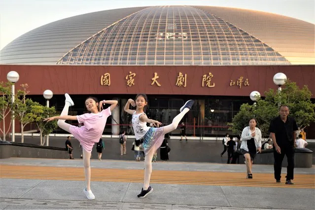 Children pose for pictures in front of the National Centre for the Performing Arts, before a performance by Russia's Bolshoi Ballet company in Beijing, China on July 25, 2023. (Photo by Thomas Peter/Reuters)